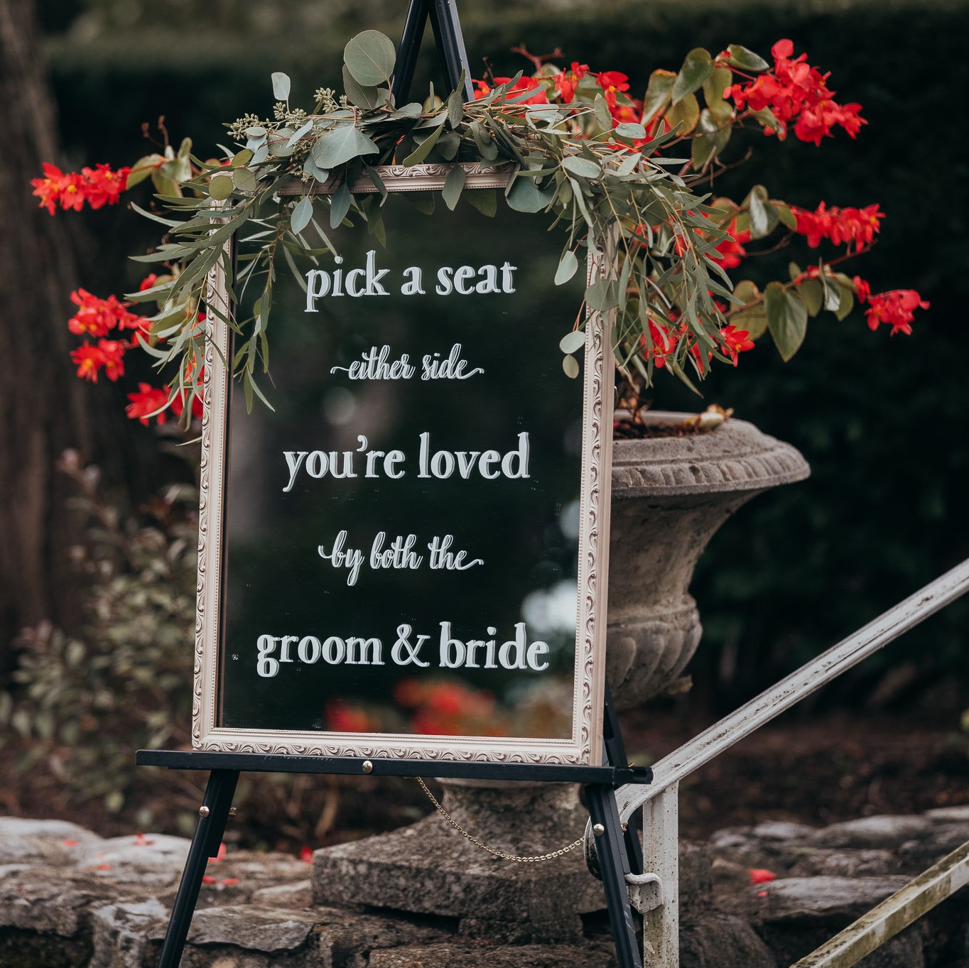 A sign that says pick a seat, you 're loved by the groom and bride.