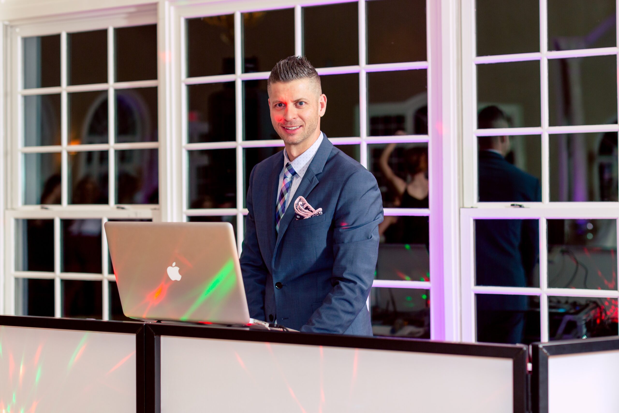 A man in a suit and tie standing at the front of a laptop.