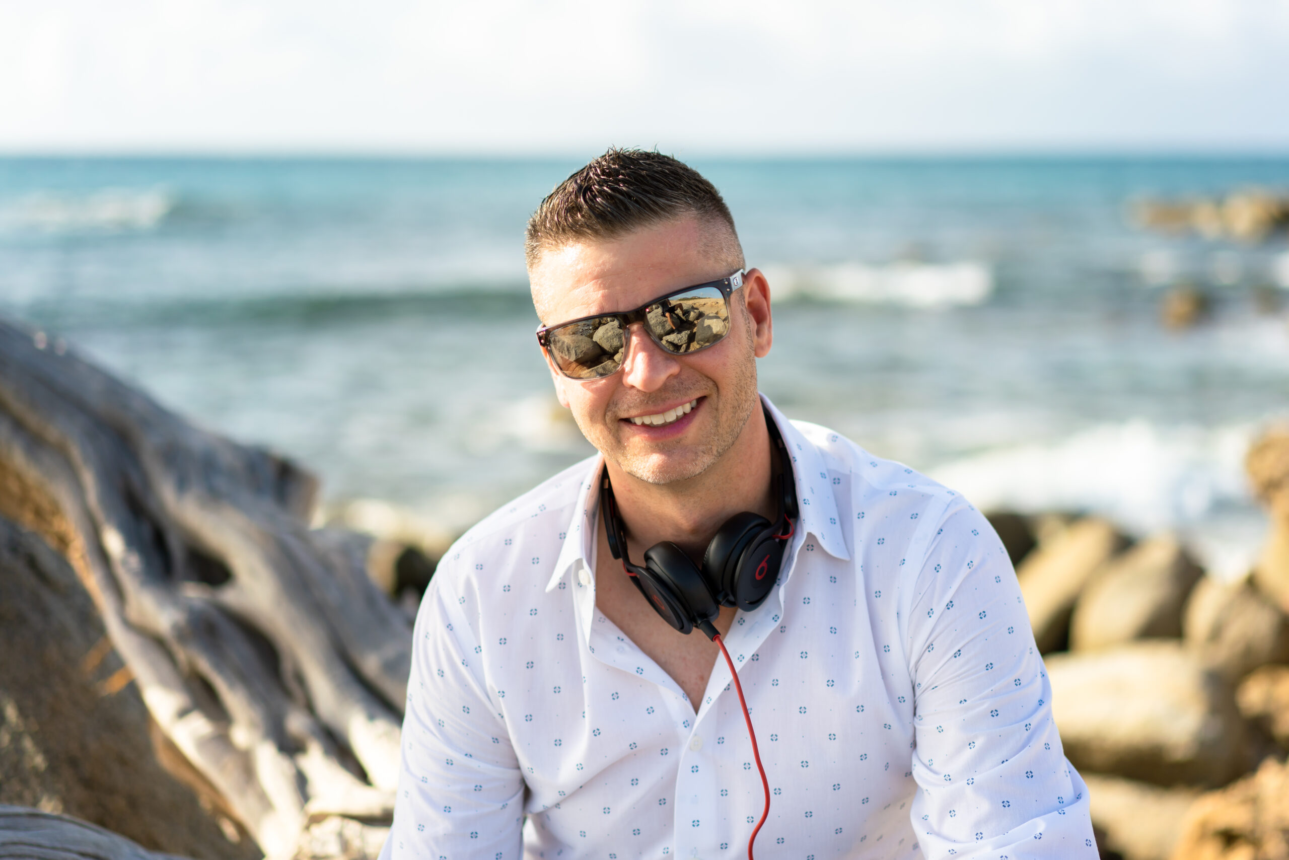 A man with headphones sitting on the beach.