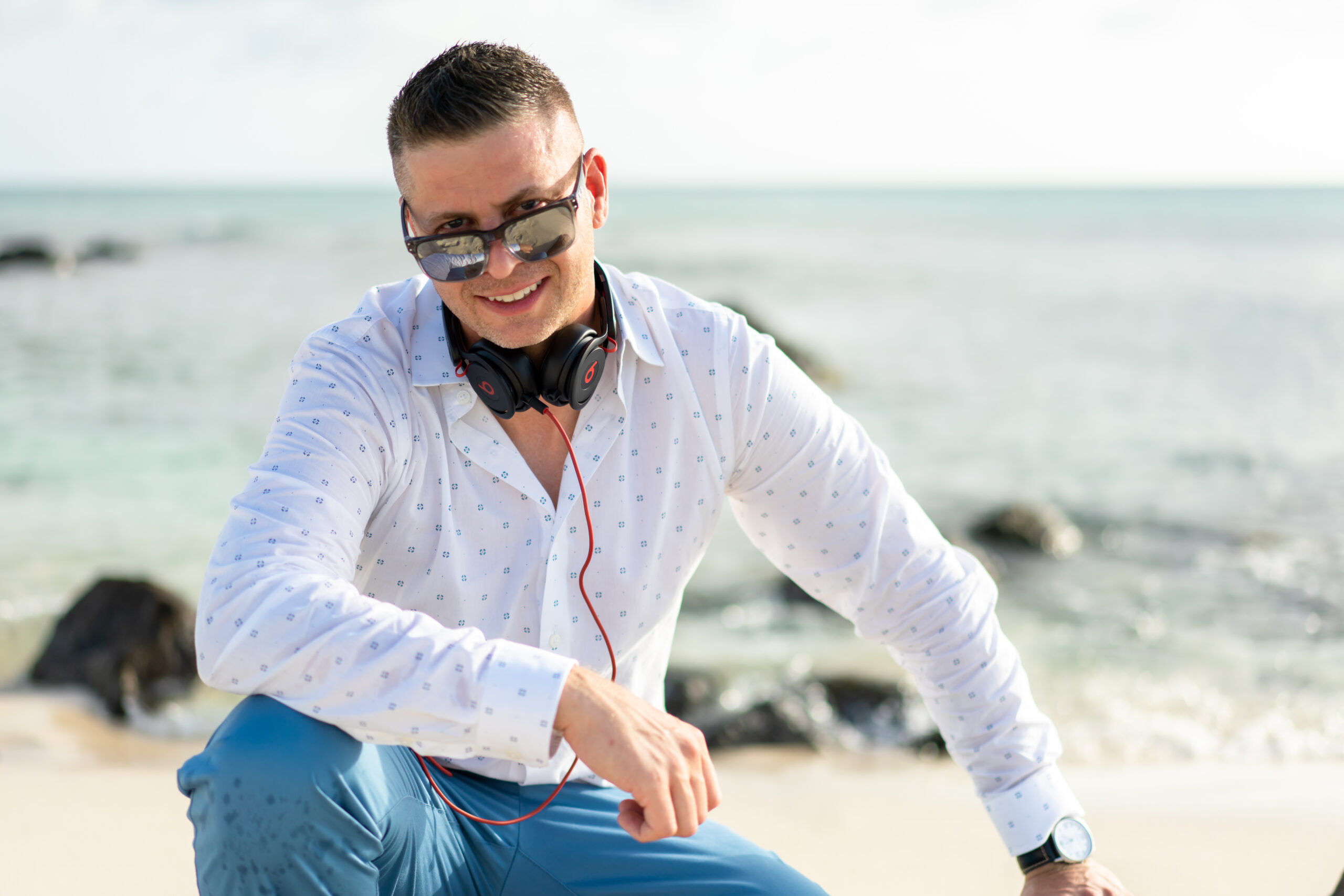 A man sitting on the beach wearing headphones.