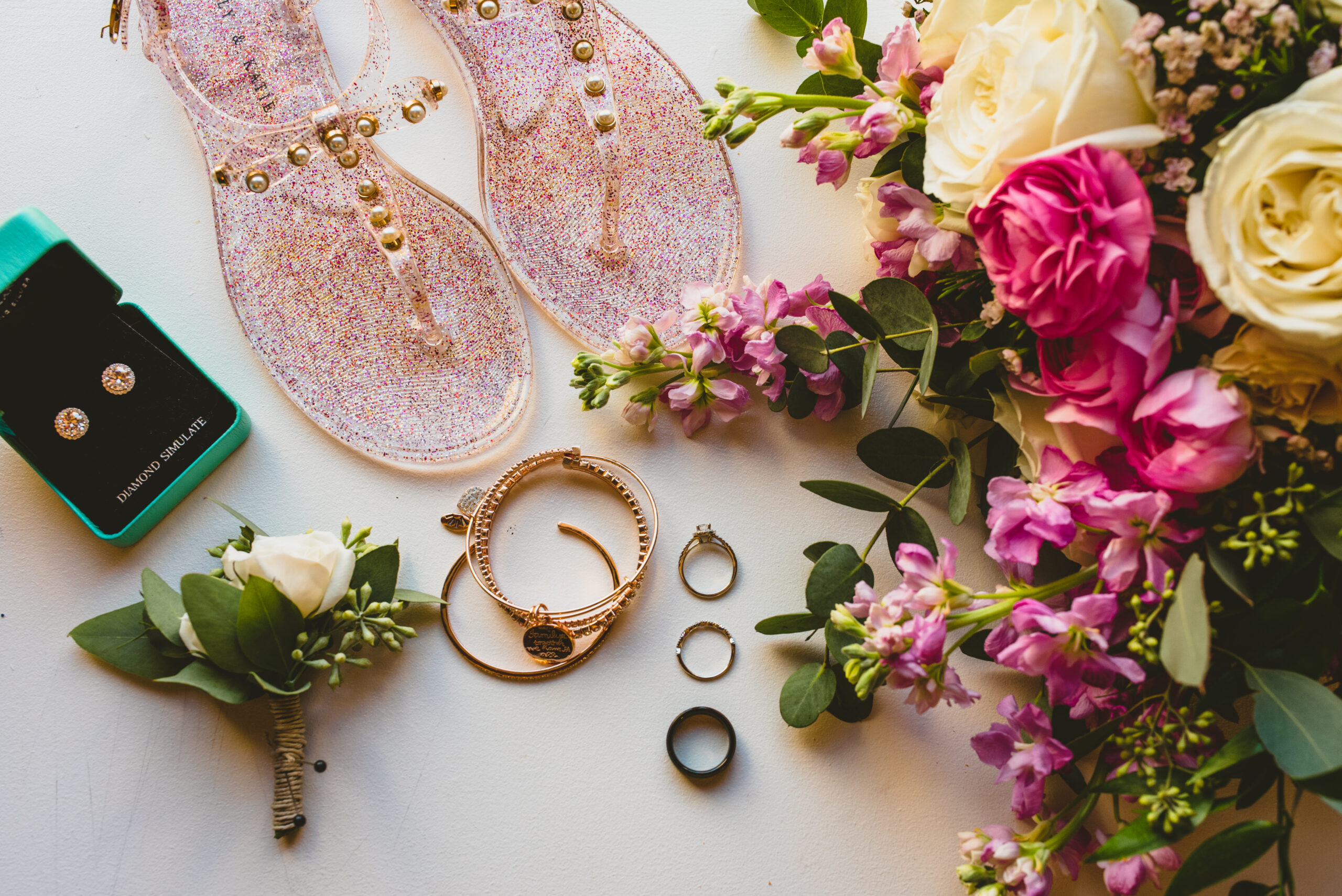 A table with flowers, rings and sandals on it.