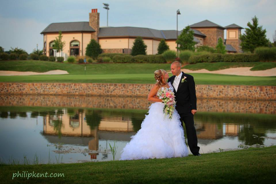 A bride and groom stand in front of the water.