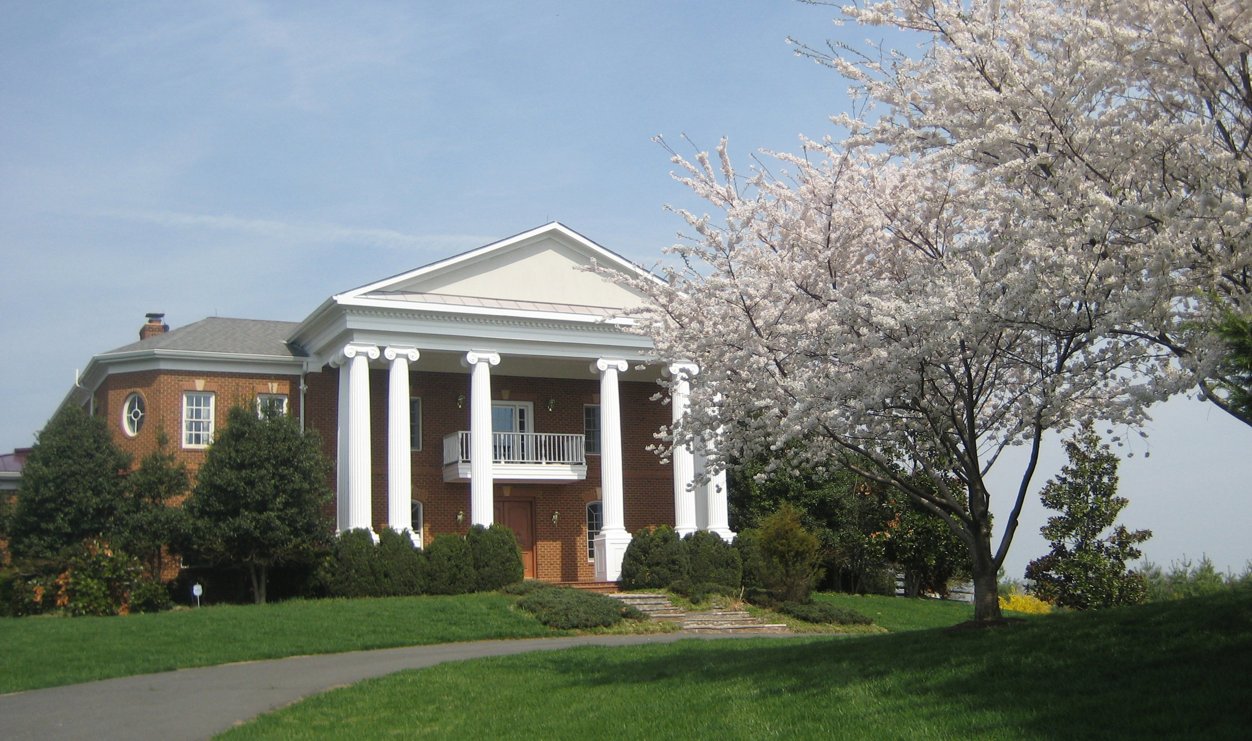 A large building with columns and a tree in the background.
